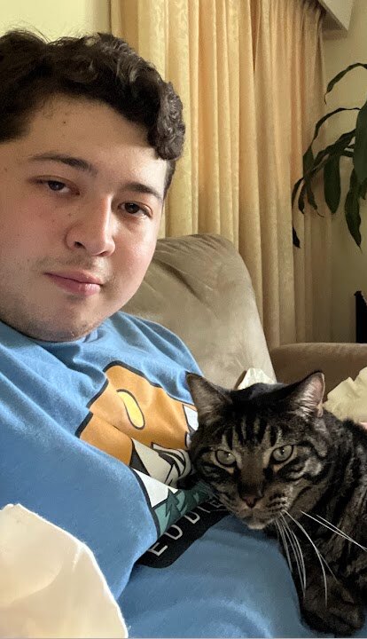 Justin sitting on a couch with a cat