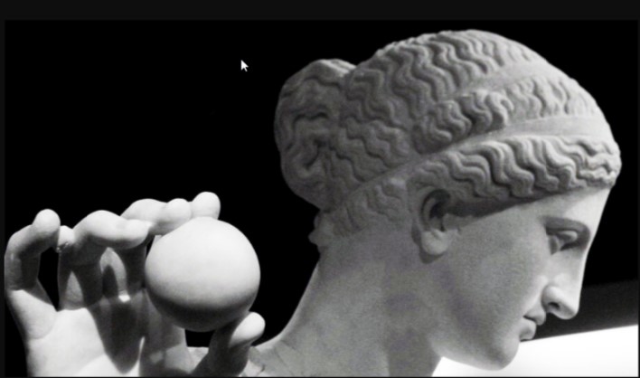 A picture of Aphrodite's statue, she's holding a sphere out to the camera but is looking to the side.