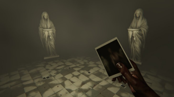 A screencap from the game MADiSON from a first person point of view, you are holding a blurry polaroid in your bloody hand and you are standing in front of two statues