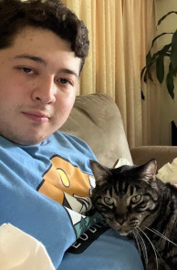 Justin sitting on a couch with a cat