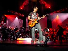 Rousing the crowd with an electrifying guitar solo (Photo by Melissa Estuesta, taken from http://videogameslive.com/gallery/v/flyers/)
