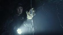 A scene from the trailer in which Daniels (Katherine Waterston) finds a piece of identification in an eerie cave. 