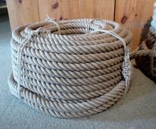 A hefty length of coiled rope sits against a wooden table